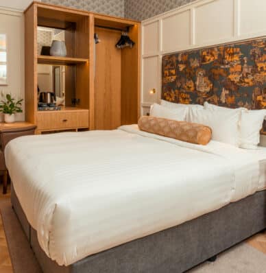 Elegant hotel room with comfy king-size bed, stylish artwork, and cosy lighting, ideal for a relaxing stay.