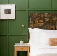 Luxurious hotel room with elegant green walls, plush white bedding, artistic headboard, and chic decor, welcoming guests.