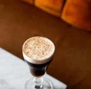 Creamy espresso martini on a marble table by a cosy amber sofa, ideal for hotel bar guests seeking cocktails and relaxed seating