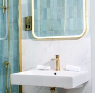 Elegant hotel bathroom with gold fixtures, modern sink, and luxurious blue tile accents.