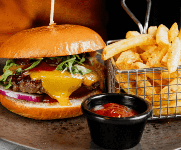 Delicious gourmet burger with melted cheese and crispy fries, perfect for a satisfying meal at our luxury hotel restaurant.