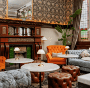 Elegant hotel lounge with plush seating, marble tables, ornate fireplace, and stained glass windows offering a cosy retreat.