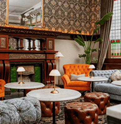 Elegant hotel lounge with plush seating, marble tables, ornate fireplace, and stained glass windows offering a cosy retreat.