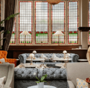 Elegant hotel lounge with plush seating, stained-glass windows, warm lighting, and coffee tables, offering a cosy atmosphere.