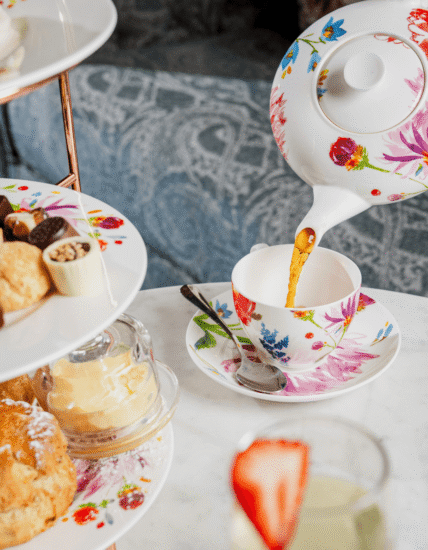 Elegant afternoon tea setup with floral china, scones, and fresh tea in a stylish hotel lounge. Luxury hospitality experience.