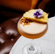 Elegant cocktail with pineapple and flower garnish on marble table at luxurious hotel lounge.