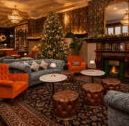 Elegant hotel lounge with Christmas tree, plush sofas, cosy fireplace, and ornate chandeliers for a warm holiday stay.